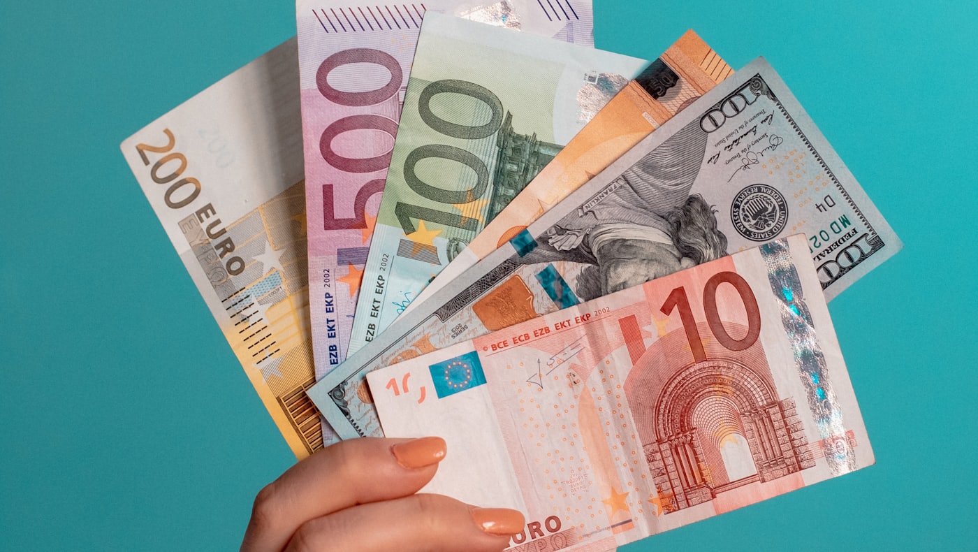 A hand holding a fan of paper banknotes
