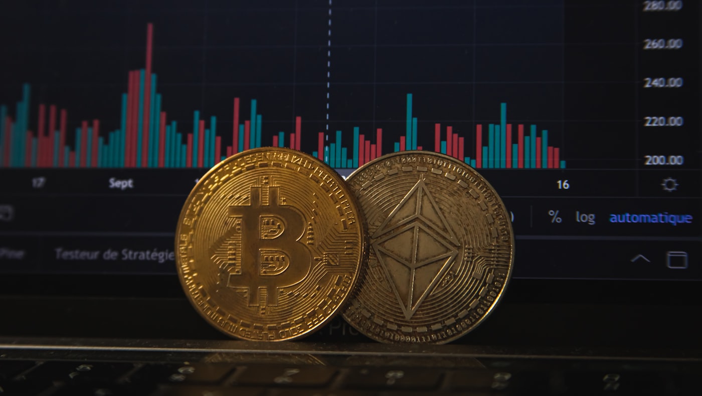 A Bitcoin coin and an Ethereum coin resting on a price chart