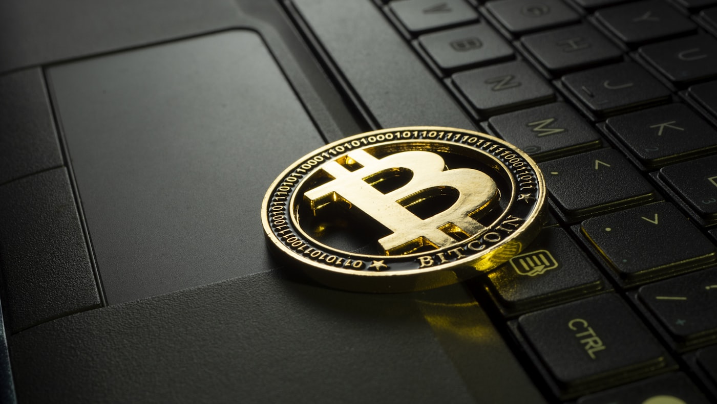 A Bitcoin coin resting on a laptop keyboard, representing holding your own crypto